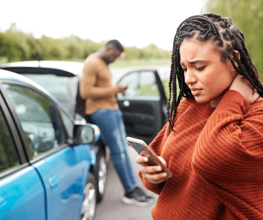 Image of woman on her phone beside a car collision