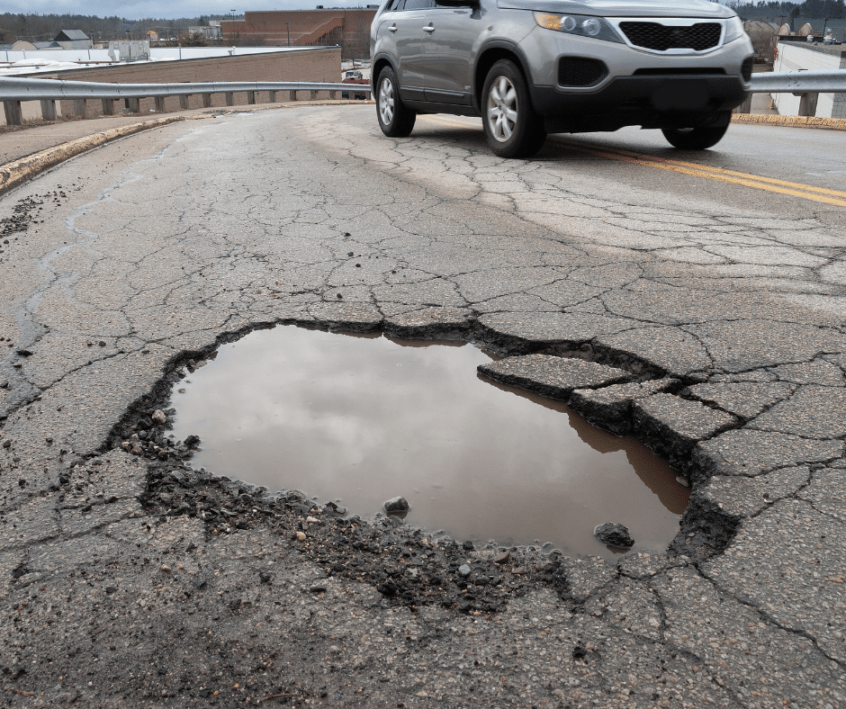 Image of pothole in road with car approaching